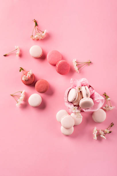 istock Rose macaroons in gift box, Cherry blossoms, empty envelope. Sweet macarons present on pink background. 1298837892