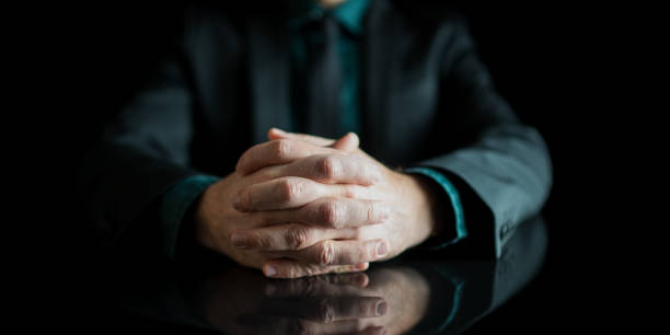 istock Businessman hands joined together resting on black desk with reflection 1298841421