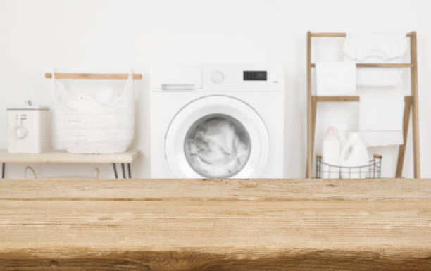 istock Wooden table in front of washing machine loaded with laundry 1298844238