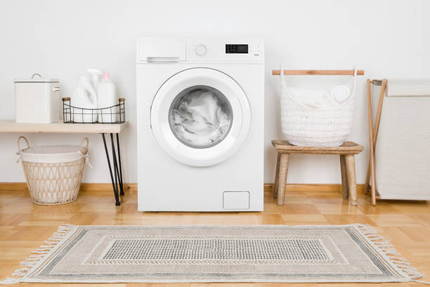 istock Laundry room with loaded washing machine, detergent bottles and textile 1298844387