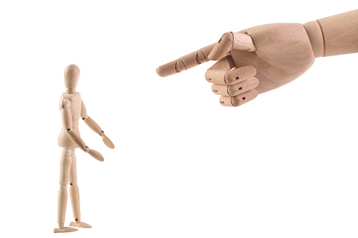 A Wooden hand pointing at a wooden mannequin
