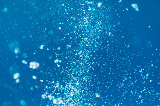 Air bubbles under the ocean in clear blue water
