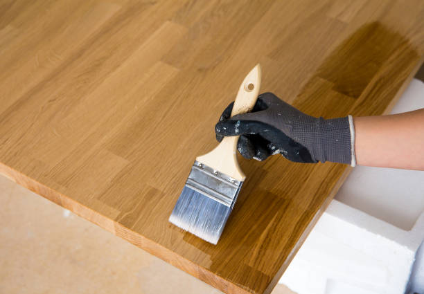 personne travaillant, huilant le comptoir de cuisine avant d’utiliser, brossant l’huile avec l’huile de graines de lissé. concept d’entretien de comptoir de bloc de boucher en bois massif. maison à l’intérieur. - wood stain photos et images de collection