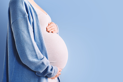 One woman, unrecognizable happy pregnant woman touching her belly.