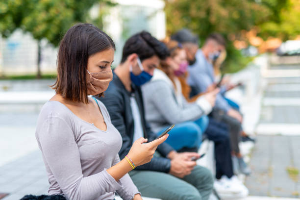 gruppe von jungen sozialen netzwerk-süchtigen auf der suche nach nachrichten auf covid19, stress von falschen informationen und negativen nachrichten, soziale isolation und stress, fokus auf brünette mädchen blick auf smartphone - emotional stress looking group of people clothing stock-fotos und bilder