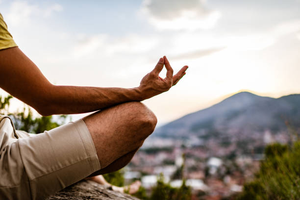 junger mann proformiert yoga in den bergen bei sonnenuntergang - zen like nature breathing exercise sitting stock-fotos und bilder