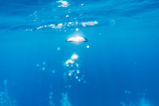 Light reflecting off an air bubble under the ocean in clear blue water