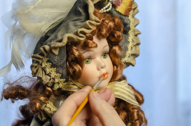 istock Hand carefully paints the doll's lips with a thin brush. 1298850734