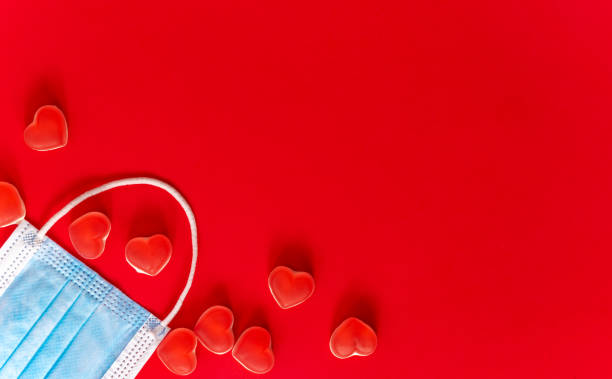 istock Blue medical mask with hearts on red background. 1298850918