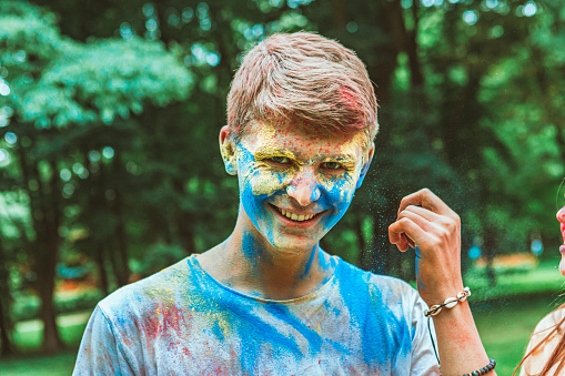 portrait of young happy man dirt in holi paints. indian fest