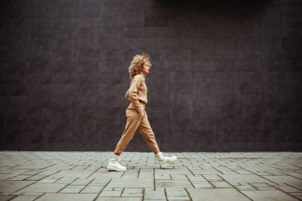 Side view of trap girl in tracksuit walking with hands in her pockets and listening music. Side view of trap girl in tracksuit walking with hands in her pockets and listening music. tracksuit stock pictures, royalty-free photos & images