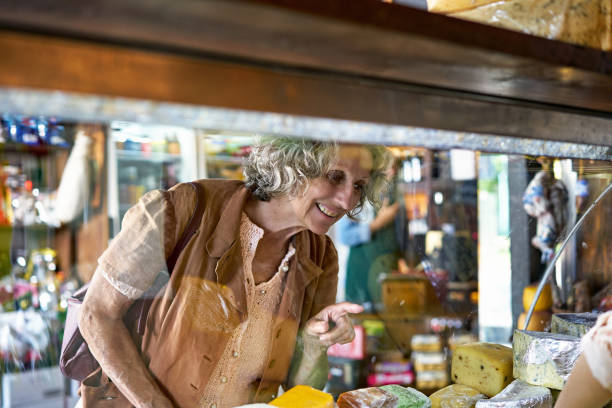 istock Smiling Senior Shopper Pointing to Cheese in Display Case 1298852868