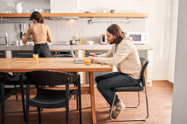 istock Man working at the laptop while his wife preparing breakfast 1298854690