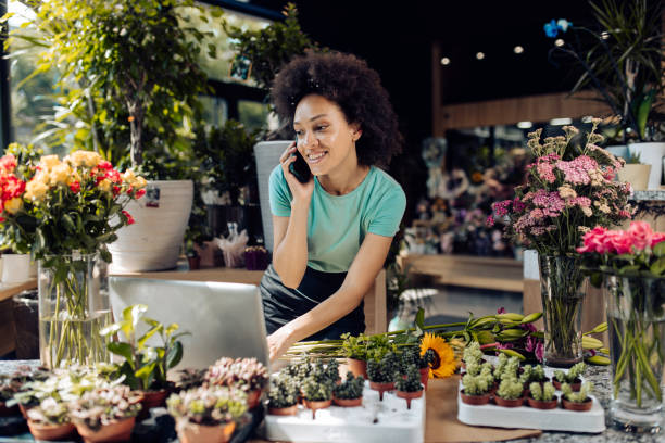istock Young florist working at her store and taking orders online 1298856177