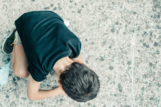 istock Black haired little boy sitting and drawing 1298856510