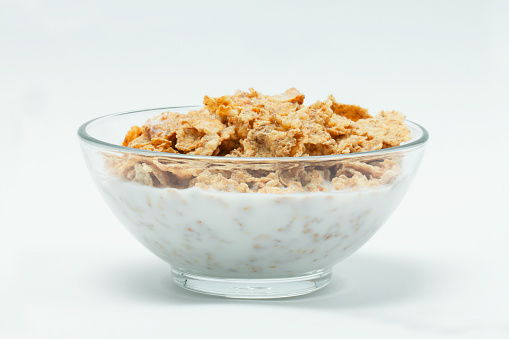 milk in transparent glass and muesli multi fruit in wooden bowl