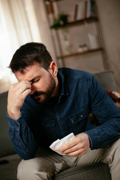 istock Young man sitting on sofa having fever 1298858644