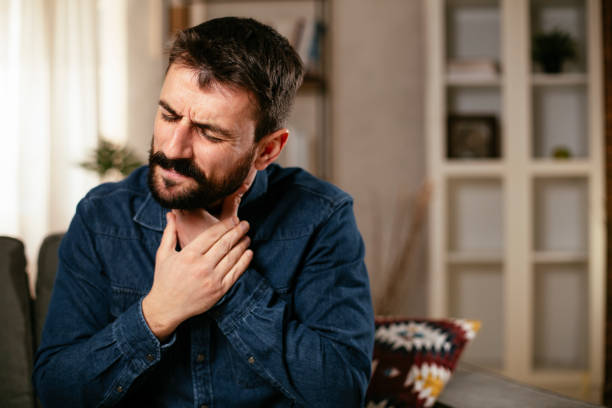 istock Young man sitting on sofa having fever 1298858882
