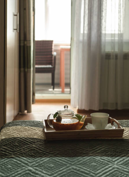 istock Wooden tray with tea and a cup stands on the bed. 1298859295