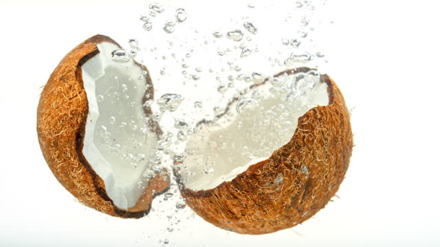SLO MO LD Two coconut halves falling into water