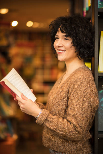 istock Happy woman standing library and holding book. 1298862862