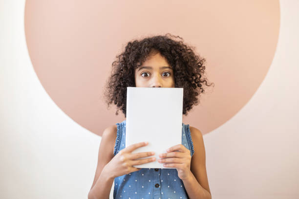 istock An African schoolgirl covers face with a book 1298863795