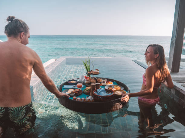 istock Lovely couple enjoy floating breakfast in private pool villa 1298864094