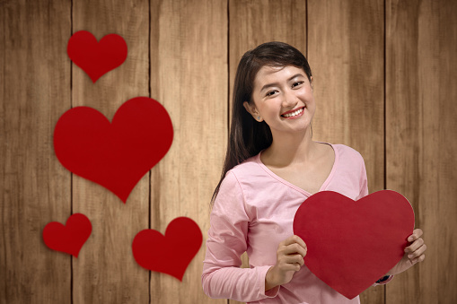 Asian woman holding the red heart with wooden background. Valentines day