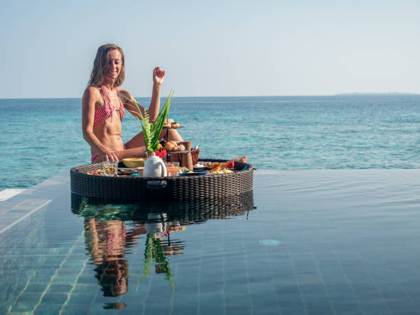 istock Beautiful young woman eats breakfast in her private pool from floating tray 1298864280