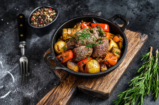 istock Meat stew in cooking pot on dark rustic cutting board. Black background. Top view 1298867532