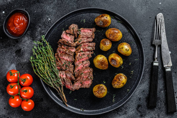 istock Flank grilled  meat beef Steak with fried potato. Black background. Top view 1298868381