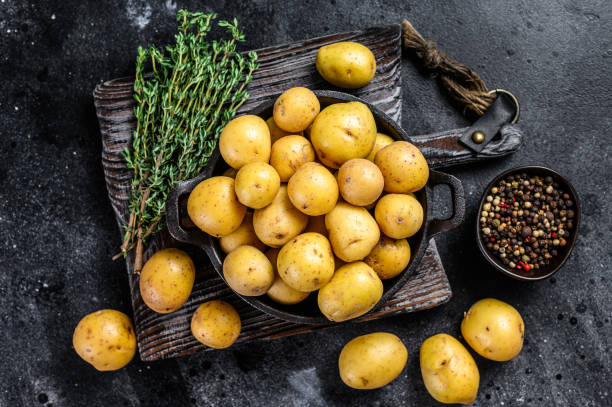 istock Young whole mini Potatoes in a pan. Black background. Top view 1298869327