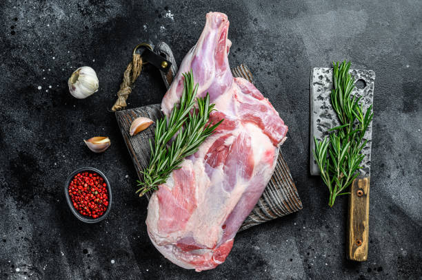 istock Raw lamb shoulder meat ready for baking with garlic, rosemary. Black background. Top view 1298871557