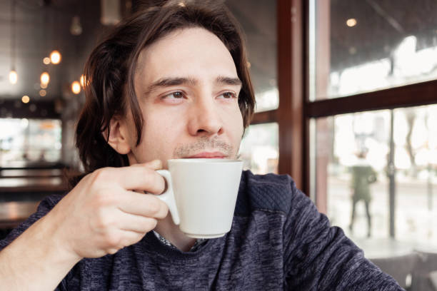 istock A man drinks coffee in a cafe, a restaurant. interior, natural sunlight, blurred background, sideways. Snack, breakfast. Lunch break. 1298873988