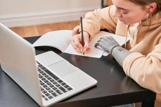 istock Woman with prosthesis arm writing at the notebook 1298875317