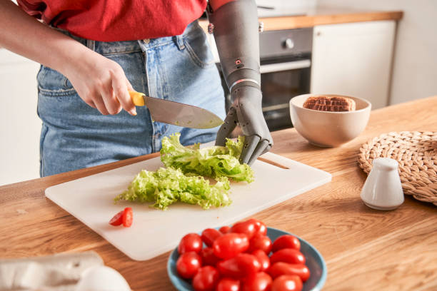 istock Woman with prosthesis arm is cutting salad on table 1298875509