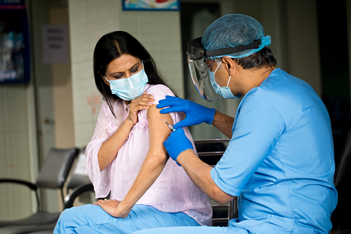 Médico inyectando vacuna a la paciente femenina photo
