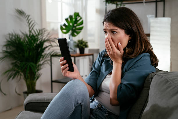 istock Sad woman sitting on the couch, using the phone 1298875941