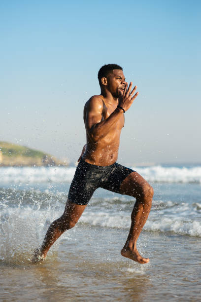 istock Black man running by the sea on summer beach training 1298877276