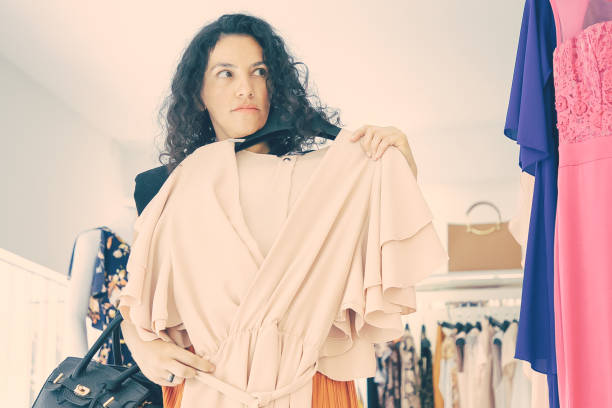istock Serious female shopper holding hanger with cloth 1298879719