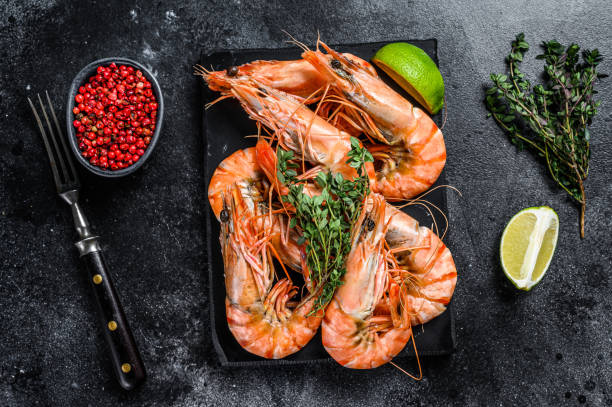 istock Red Langostino shrimps Prawns on a marble board.  Black background. Top view 1298880421