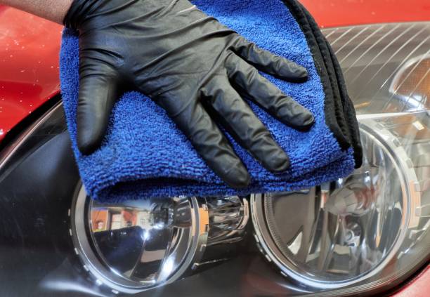 gloved hand of a mechanic wiping the headlights of a car with a cloth after having polished them and leaving them restored and shiny - lava lamp imagens e fotografias de stock