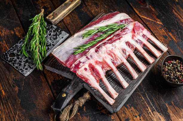 rack de carne crua de cordeiro com osso em uma tábua de corte. fundo de madeira escura. vista superior - rack of lamb - fotografias e filmes do acervo