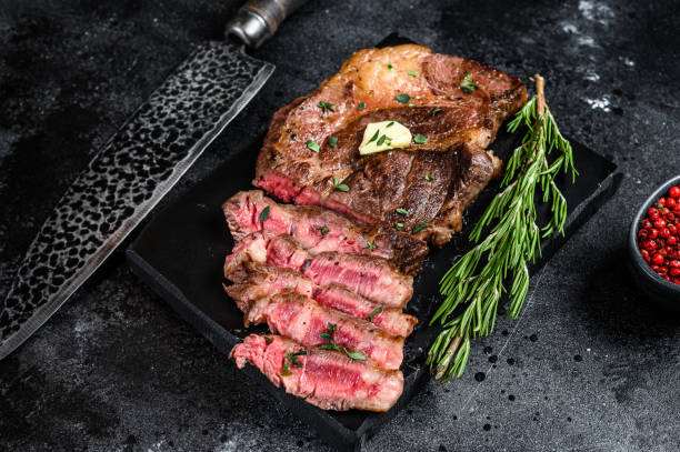 istock Cut Grilled Chuck eye roll beef meat steak on a marble board. Black background. Top view 1298884368