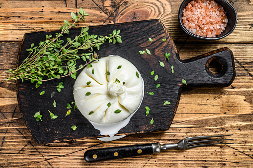 Cheese Burrata mozzarella on a wooden cutting board. wooden background. Top view.