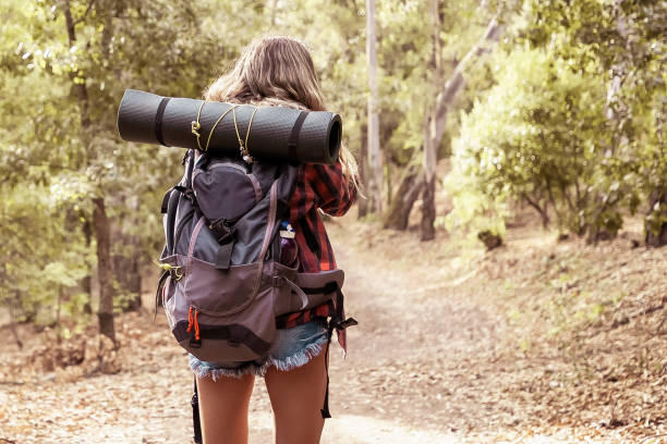 istock Back view of woman walking on nature with backpack 1298885402