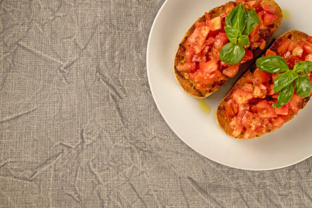 istock Two bruschetta (toasted bread) with tomato and basil on the white plate. 1298887810
