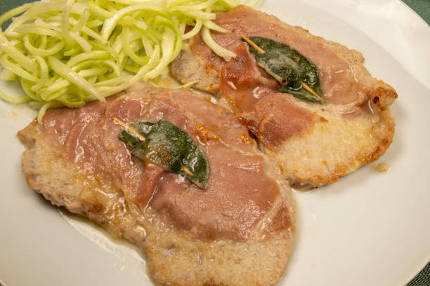 Saltimbocca alla romana (veal with raw ham and sage) with a side of puntarelle in close-up. Saltimbocca alla romana (veal with raw ham and sage) with a side of puntarelle in close-up. Typical second course of Roman cuisine. puntarelle stock pictures, royalty-free photos & images