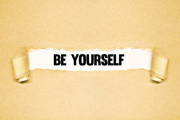 Torn paper revealing words BE YOURSELF stock photo