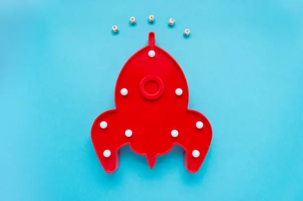 Red rocket ship lamp and the inscription space on blue background. Cosmonautics Day concept. Top view